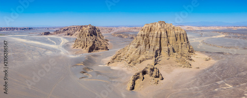 Two giant clay rock towers in a yardang desert landscape under a blue sky in the Gobi Desert, Dahaidao, Xinjiang, China