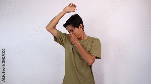 Photos Asian young man gestures smelling armpit and covering his nose