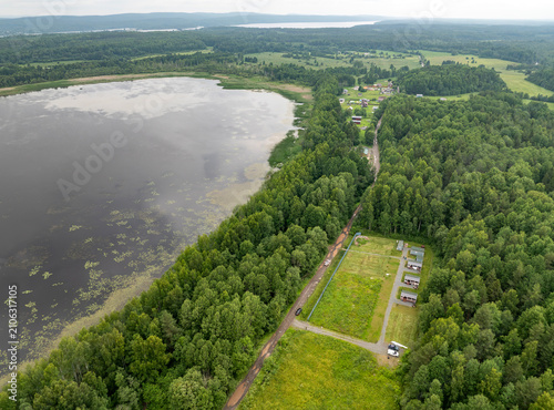 Aerial view of a small holiday resort and sub-divided land plots by a quiet forest lake on an overcast summer day in Karelia, Russia