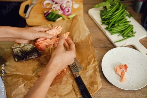 Top view of hands tearing hot smoked pink salmon into pieces
