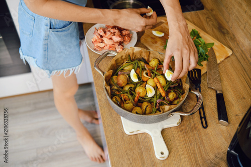 Cooking vegetables and eggs in kitchen near plate with fish