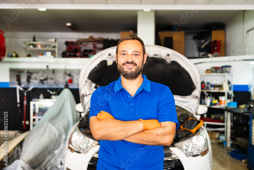 Mechanic smiling with arms crossed in auto workshop