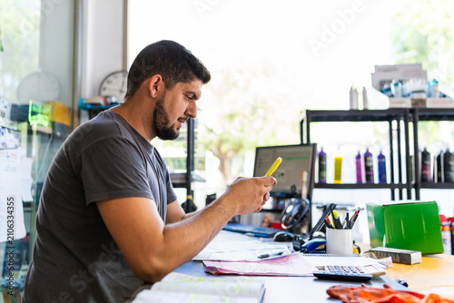 Workshop owner using smartphone managing business activities