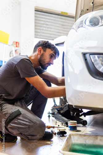 Quadro su tela Mechanic repairing car wheel in auto workshop