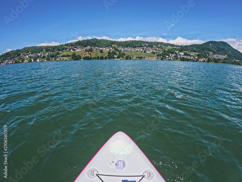 Foto Stand up paddleboarding POV in a lake surrounded by hills during a summer day