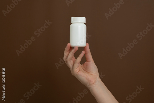 Hand holding white medicine bottle for health