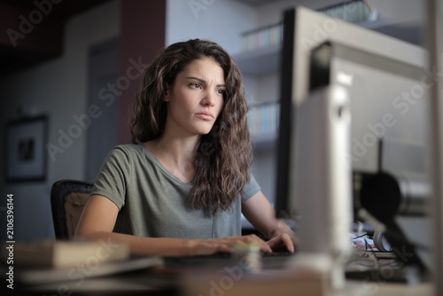 Confused young woman frowning at her computer screen