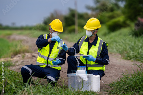 Two professional agricultural scientists or environmental inspectors testing water quality in a flask during field research for soil and water contamination, focusing on sustainable farming ecology.
