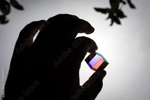Fotografie Geometric cube glows with saturated pink while a hand forms a circle around it s