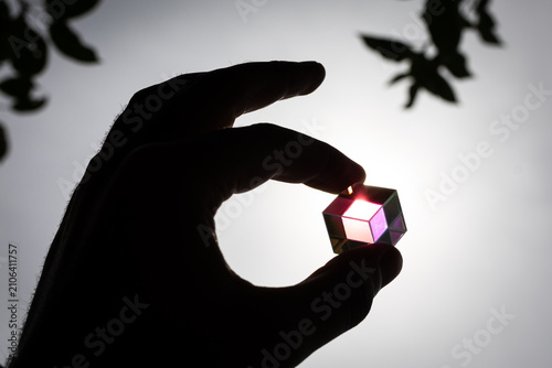 Konstfotografi Backlit dichroic cube centered in a fingertip grip radiates playful color and cl