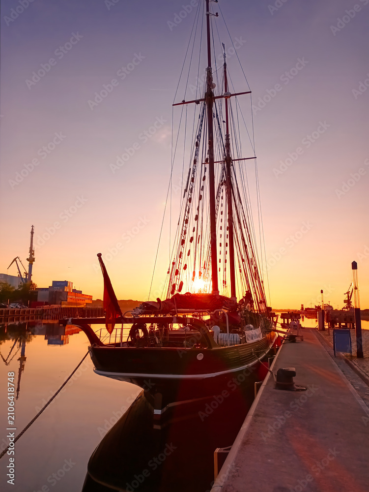 Fototapeta premium Segelschiff im Sonnenuntergang im Hafen von Wismar