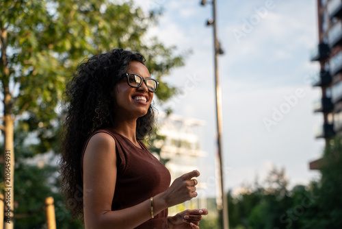 Smiling latina woman using AR glasses in city park