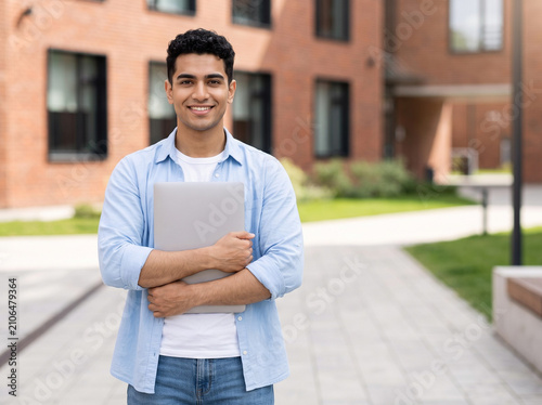 young fair skinned indian college student holding laptop at university campus promoting higher education student finance study abroad and career growth