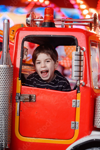 Intensely screaming boy inside red car ride frame close up portrait funfair