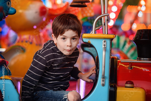 Low angle boy pensive holding steering wheel high in red car ride blue sky prop