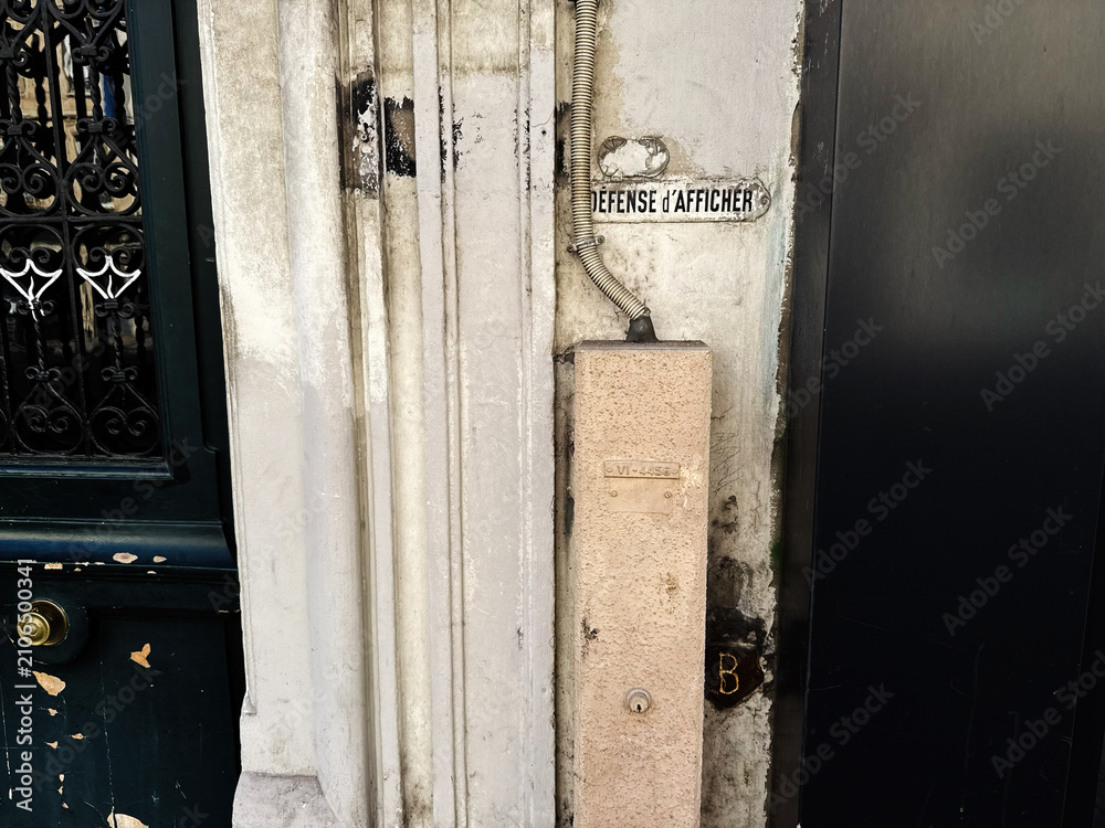 Fototapeta premium Weathered doorway and vintage sign on a Paris, France building wall with textured plaster and metal gate detail