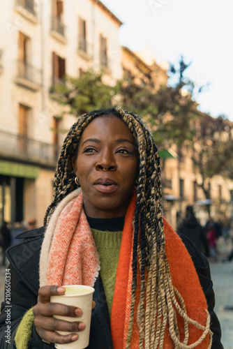 Young black woman enjoying coffee in city street