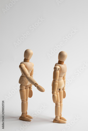 Another wooden figure reaching out its hand to the wooden figure with its back turned