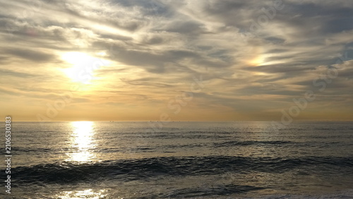 Fotografie Dramatic Cloudy Sky with Bright Sun Reflecting on Ocean