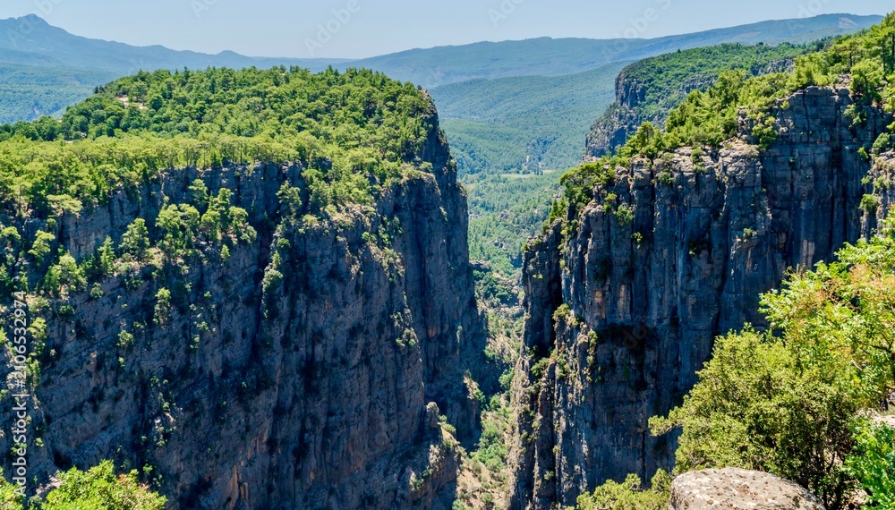 Fototapeta premium Antalya, Turkey - July 15, 2026: View of Tazy Canyon in Antalya, Turkey, showing dramatic rocky cliffs, deep canyon landscape, green forested slopes, natural rock formations, and scenic views