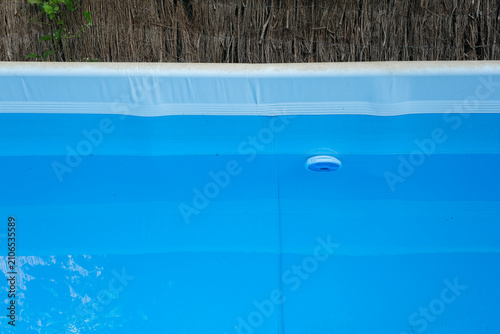 Fragment of a frame pool in the backyard with a chlorine dispenser. Home pool maintenance. Minimal, copy space.