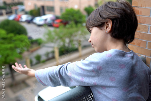 Obraz na płótnie Young individual with short brown hair reflects quietly while leaning on balcony