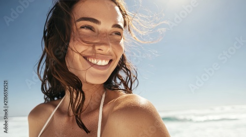 Joyful woman smiling in sunlight by the ocean on a beautiful summer day