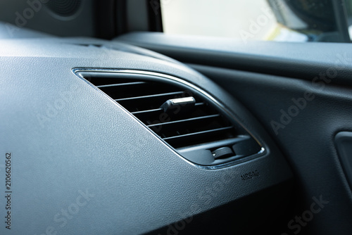Cuadro en lienzo Close up of a car dashboard air vent with chrome trim positioned above a subtle airbag warning sign on dark leather