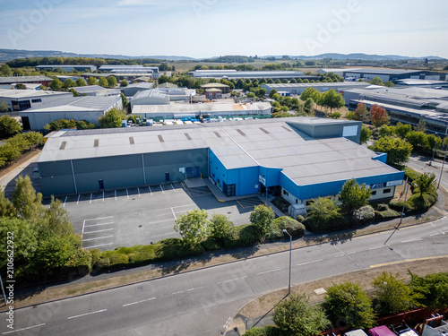 Aerial View of Modern Industrial Warehouse Complex in Green Countryside at Sunset – Commercial Buildings in Rural Setting