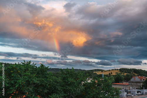 Rainbow on a stormy sky, with wind turbines and a GSM mast in the background, Kamienna Góra, Poland.
