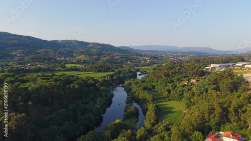 Lima River Flowing Through Lush Forested Valley And Verdant Vineyards Near Town Of Ponte de Lima, Portugal. aerial shot