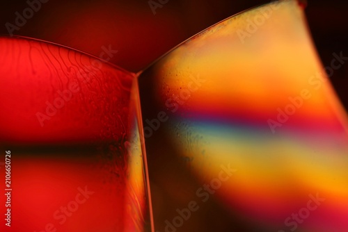 Crimson and rainbow fluid corner macro with spectral iridescence. Abstract horizontal macro photography of a liquid angular junction.