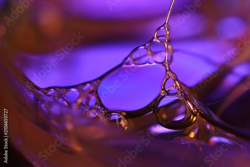 Abstract macro photography of a multi-tiered liquid framework. Luminous purple and violet light illuminates a complex 3D network of compartments, fine junctions, and transparent membranes a