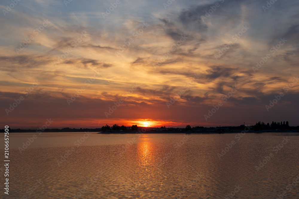 Obraz premium Vibrant sunset reflecting on the water of Lake Morii in Bucharest, Romania