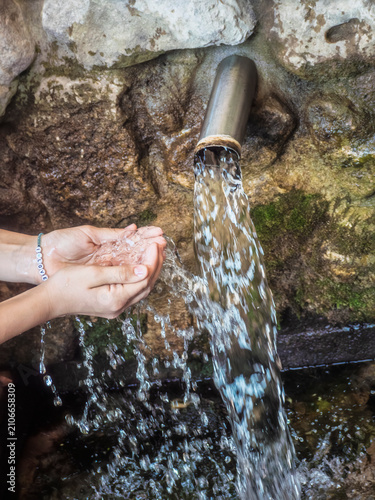 Fotografie Hands cupping fresh mountain spring water flowing from a natural pipe