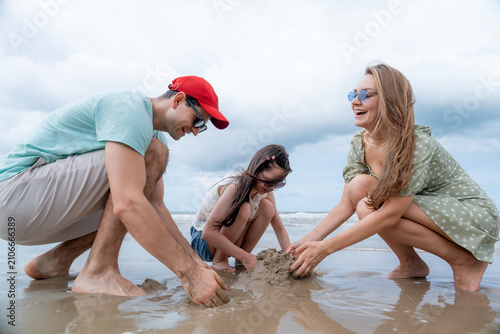 Parents and daughter enjoy building a sandcastle on a tropical beach creating meaningful family moments with happiness togetherness and unforgettable summer vacation memories.
