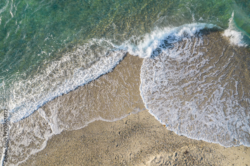 Relaxing aerial beach view with calm sea water and stone, slabs, lump, coral. Summer vacation. Blue ocean lagoon, sea shore, coastline. Drone, copter top view.