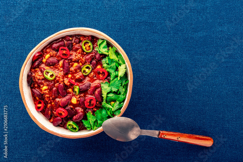 Spicy chili con carne, traditional Mexican beef stew. Flat lay on blue background