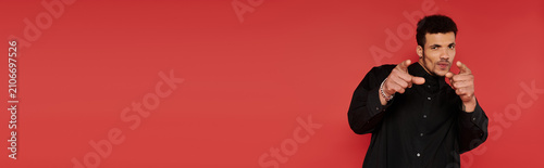 Foto A black man, handsome man playfully gestures with a confident smile by a red wall