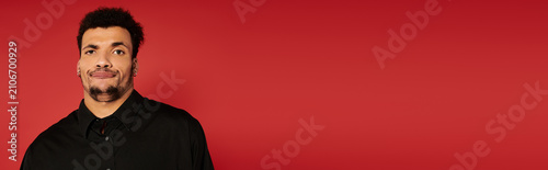 фотографія A young handsome man stands with a relaxed expression in front of a bold red backdrop
