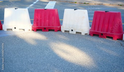 Photography Row of red and white plastic plastic traffic barriers blocking an asphalt road