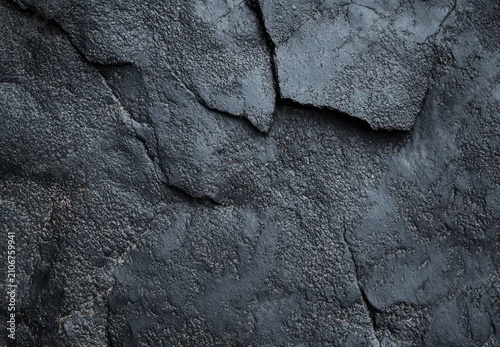 somber rugged cracked dark rock surface with layered fissures and granular texture