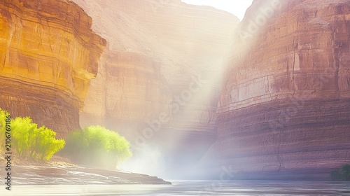 Massive canyon cliffs with a river flowing through a misty, sunlit valley during summer