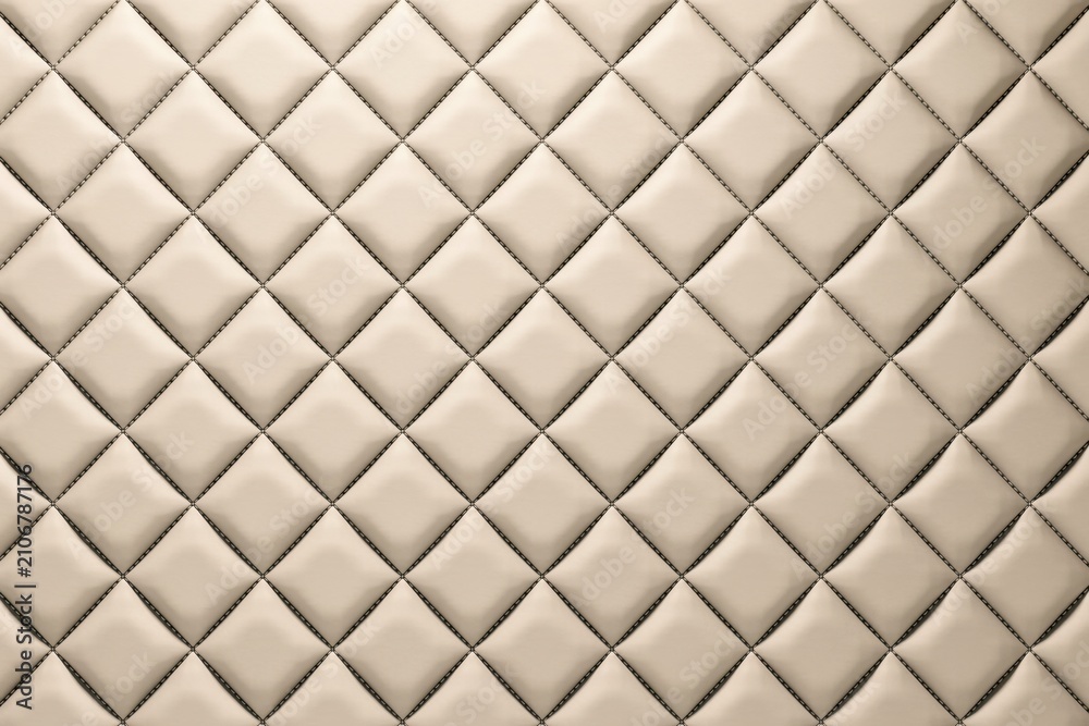 Obraz premium A seamless background, texture of beige, leather upholstery featuring, a classic diamond, quilted pattern with, dark stitching in, a grid arrangement