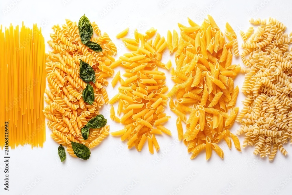 Fototapeta premium assorted uncooked yellow pasta varieties arranged in neat rows with fresh basil leaves on a bright white background, vibrant and appetizing