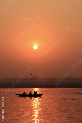 Silhouettes of passengers aboard wooden boats at sunrise on the Ganges River in Varanasi, India