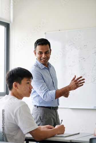 Male Teacher Explaining Lesson to Student at Whiteboard