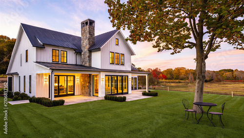Cuadro en lienzo Modern farmhouse style home at twilight with warm interior lighting real estate