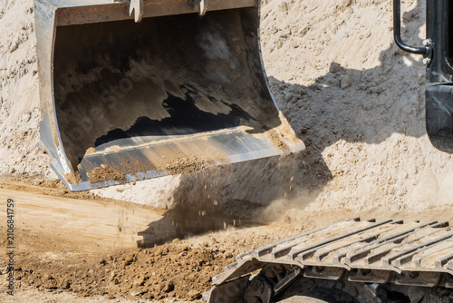Bild auf Leinwand Wide toothless grading bucket dumping loose subbase soil and sand during precisi