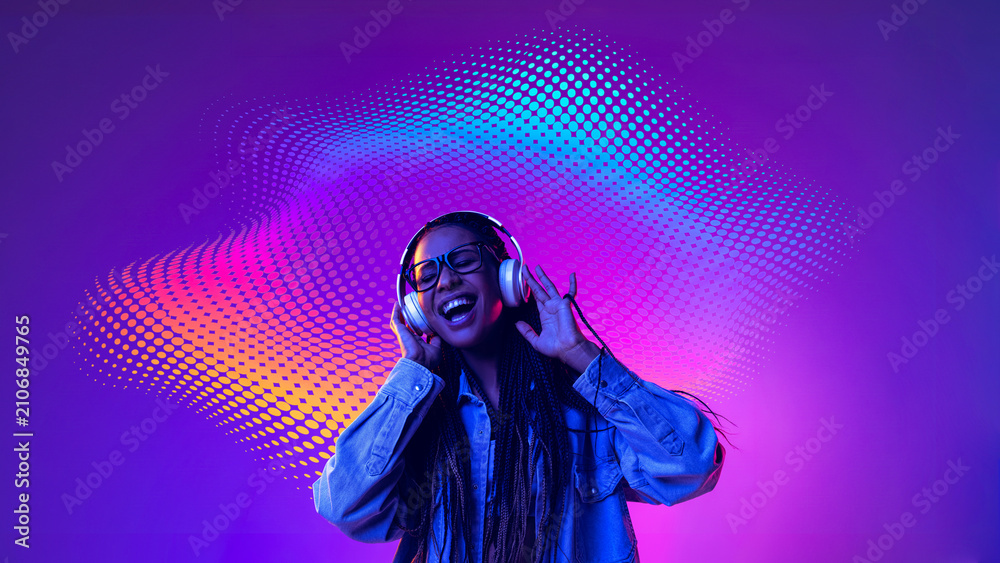 Naklejka premium Smiling woman enjoying headphones with colorful digital sound waves. Concept of joyful music experience, streaming service advertising, music festival promotion.